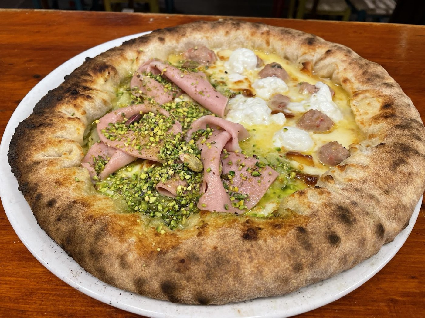 Pizza con mortadella, pistacchio e stracciatella, cornicione alto e ben cotto